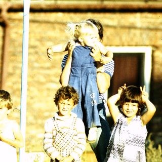 Five children playing on a swing set outdoors.