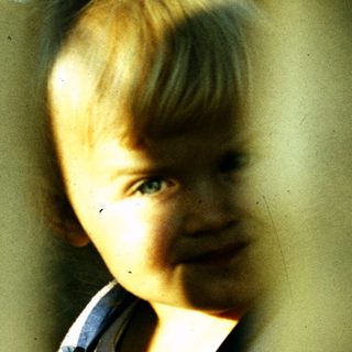 Young child smiling through window bars.