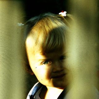 Young child smiling through window bars.