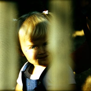 Young child smiling through window bars.