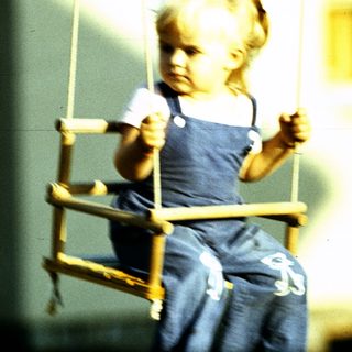 Child swinging on a swing outdoors.