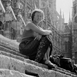 Woman sitting on cathedral steps in Gothic architecture.