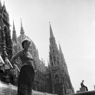 Woman posing on cathedral steps with suitcase.