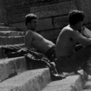Woman posing on cathedral steps with suitcase.