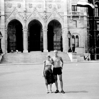 Two people posing in front of grand historic building.