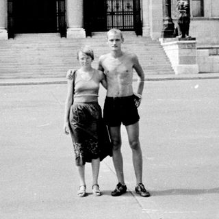 Two people posing in front of grand historic building.