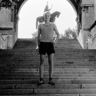 Person standing on wide stone staircase under archway.