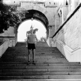 Person standing on wide stone staircase under archway.