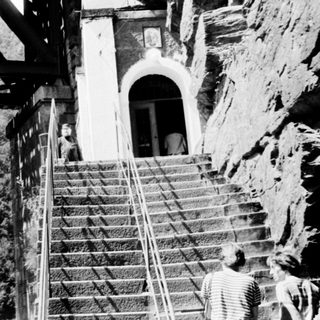 Staircase leading to cliffside building with bridge above.