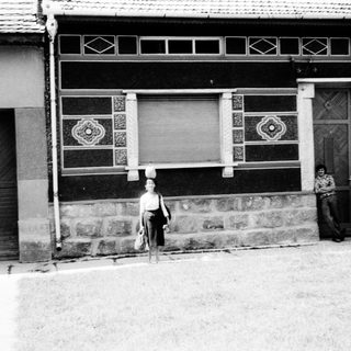 Vintage street scene with traditional building and three people.