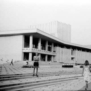 Modernist building with classical elements, people walking outside.