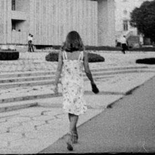 Modernist building with classical elements, people walking outside.