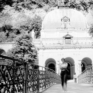 A person walking on a bridge toward grand domed building.