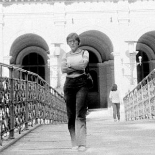 A person walking on a bridge toward grand domed building.