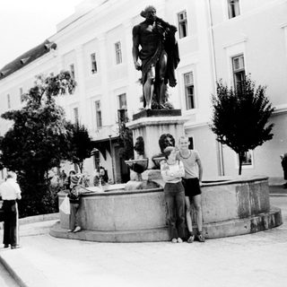 People posing near classical statue fountain in courtyard.
