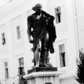 People posing near classical statue fountain in courtyard.