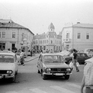 Vintage urban street scene with parked cars and pedestrians.