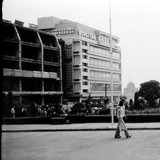 Urban plaza with mid-century buildings and pedestrians.