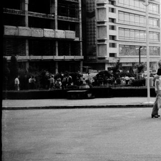 Urban plaza with mid-century buildings and pedestrians.
