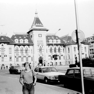 Historic building with classic architecture, person posing outside.