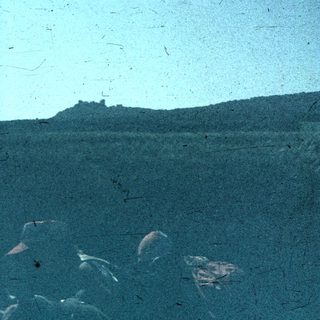 Blurred coastal landscape with distant hilltop ruins.