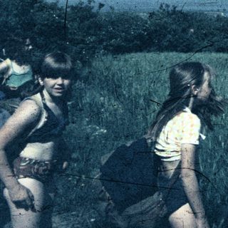 Two people hiking through tall grass.