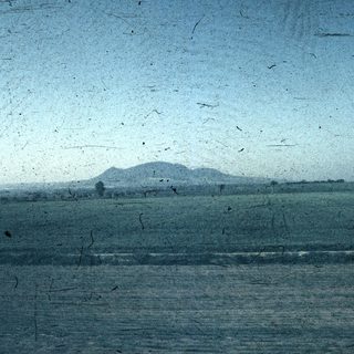 Blurry coastal landscape with distant hills.