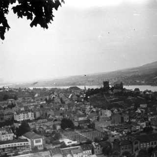 Historic cityscape by waterfront with hilly terrain.