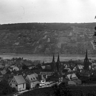 Historic village with church spires and terraced hills.