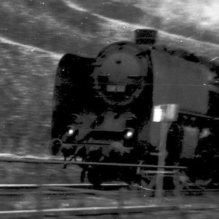 Steam locomotive traveling through wet tracks.