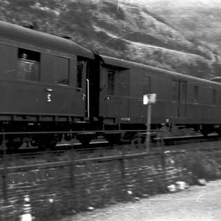 Steam-era passenger train on tracks.