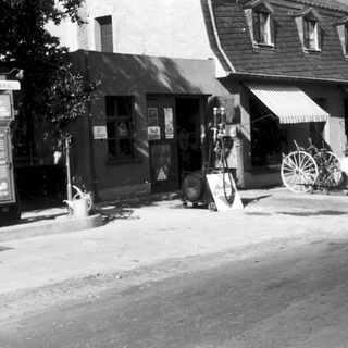 Vintage gas station with small storefront and old vehicles.