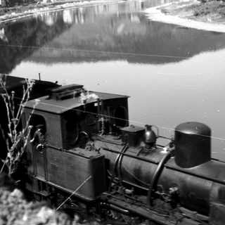 Steam locomotive near waterway, early 20th century.