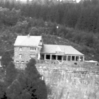 Architectural dam with adjacent buildings on hillside.