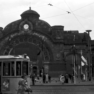 Historic train station with vintage tram and flags.