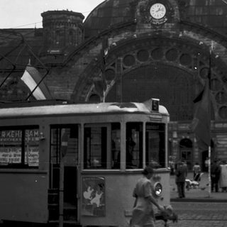 Historic train station with vintage tram and flags.