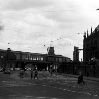 Bombed railway station with smoke and wartime chaos.
