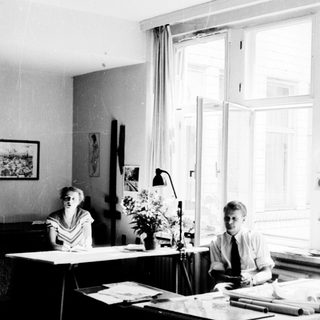 Two people working at desks in a bright office.