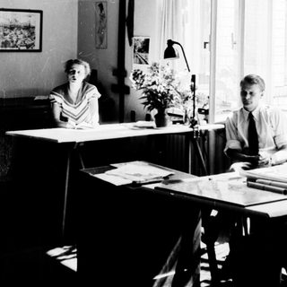 Two people working at desks in a bright office.