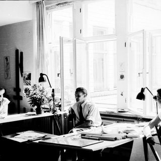 Three people working collaboratively in a bright studio.