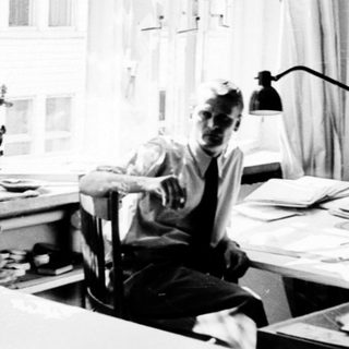 Three people working in a bright, cluttered study.