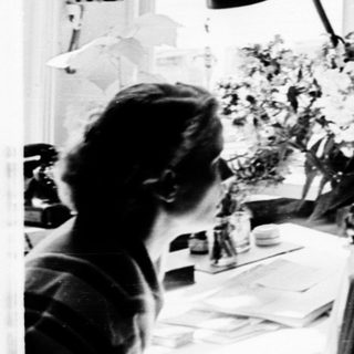 Three people working in a bright, cluttered study.