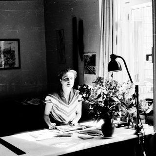 A woman writing at a desk with natural light.