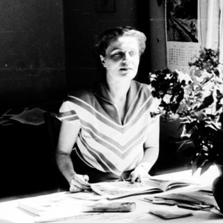 A woman writing at a desk with natural light.