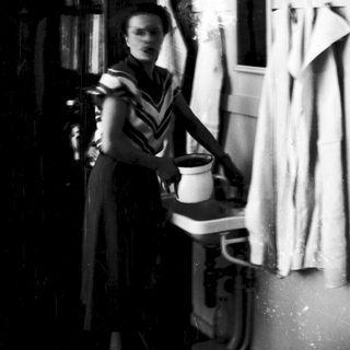 A woman in vintage attire ironing clothes indoors.