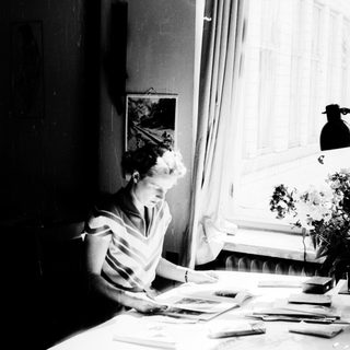 Woman sewing by a sunny window.