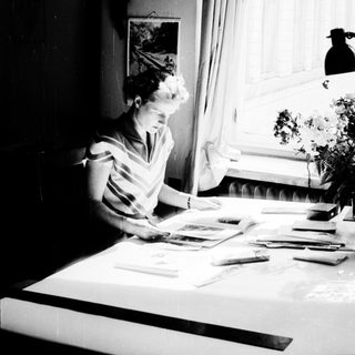 Woman sewing by a sunny window.