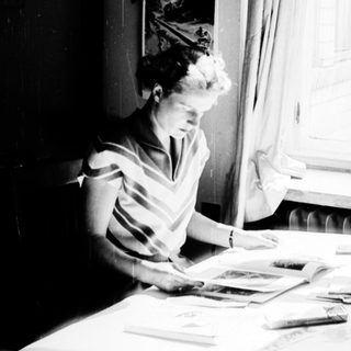 Woman sewing by a sunny window.