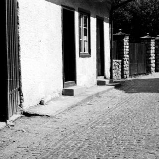 Two adults and child walking on cobblestone path.