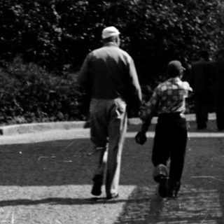 Two adults and child walking on cobblestone path.